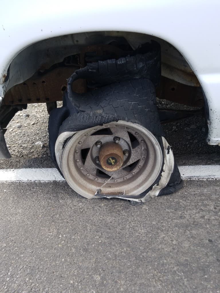 Shredded tire peeled off the wheel of a work van, still sitting in the wheel well